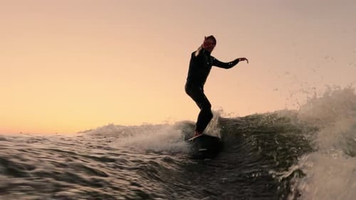 An Enthusiastic Surfer Riding the Waves at Sunset Capturing the Thrill of Surfing Amidst a Beautiful