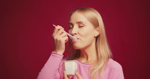 Woman Enjoys Eating Yogurt from Container on Set