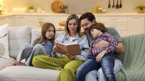Happy family reading book and spending time together on sofa in kitchen at home