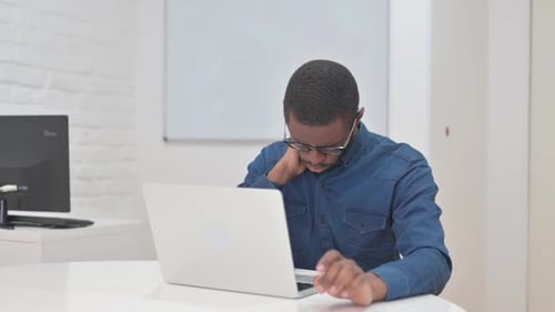 Man working on laptop with neck pain