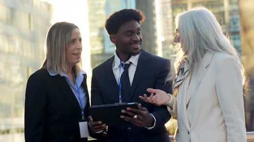 Business Team Discussing Ideas on a Tablet Outdoors