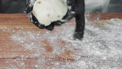 Hands Kneading Dough on Wood Surface