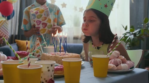 Girl Blowing Candles on Birthday Cake with Friends