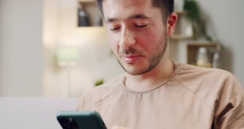 Close Up of Caucasian Young Man Sitting on Sofa in Living Room Holding Smartphone and Chatting