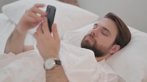 Man Lying in Bed Using Smartphone