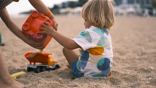 Kinder spielen mit Schaufel und Eimer im Sand am Strand