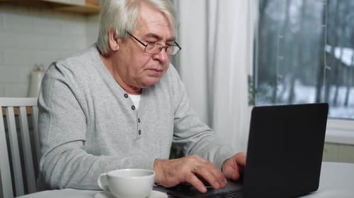 Mature Adult Typing on Laptop at Home