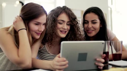 Smiling Young Women Friends Using a Tablet