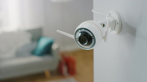 Close Up Object Shot of a Modern Wi-Fi Surveillance Camera with Two Antennas on a White Wall in a C