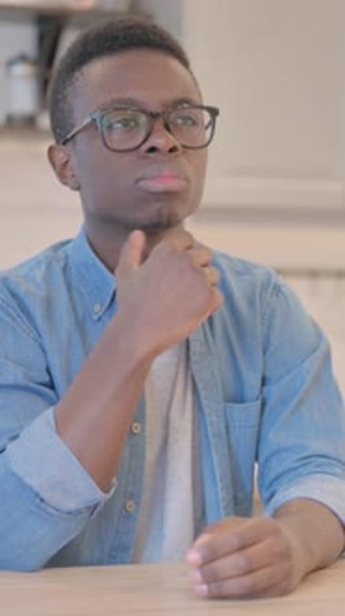 Young Man with Glasses Thinking Deeply Indoors
