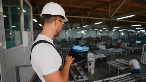 Foreman With Laptop On PVC Windows Factory Analyzes The Production Process