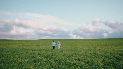 Couple joyeux à la campagne dans la nature Un homme et une femme se promènent dans un champ de colza