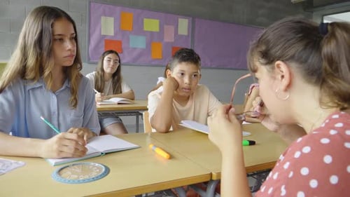Young Female Teacher in a Classroom with Primary School Students Children at Desks in Class