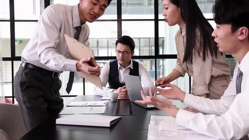 Frustrated business colleagues in office environment having heated argument over documents, pointing