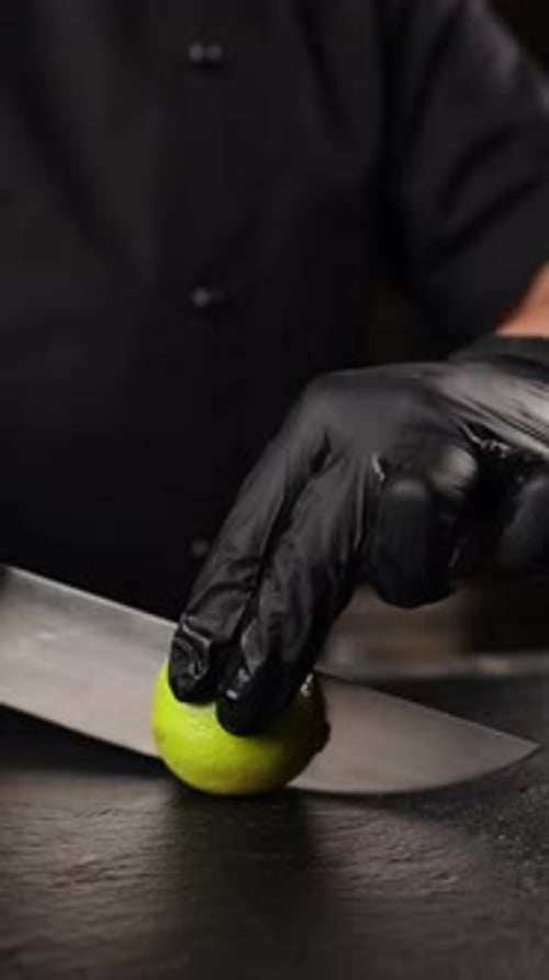 A cook is cutting limes in the kitchen. Close up