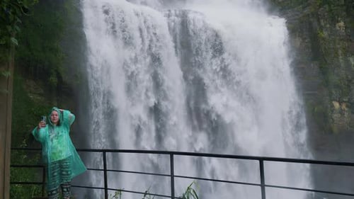 Female Tourist in Raincoat Filming Herself Against Waterfall Ramboda Falls