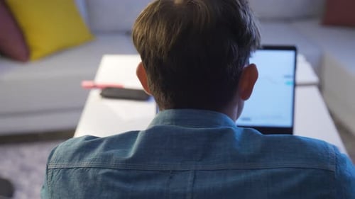 Young Adult Analyzes Financial Data on Laptop