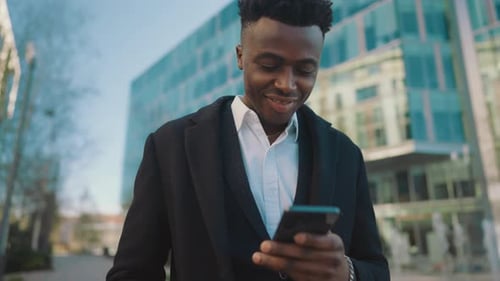 Joyful Black Man with Smartphone on City Street Portrait Outdoors Read Message African American