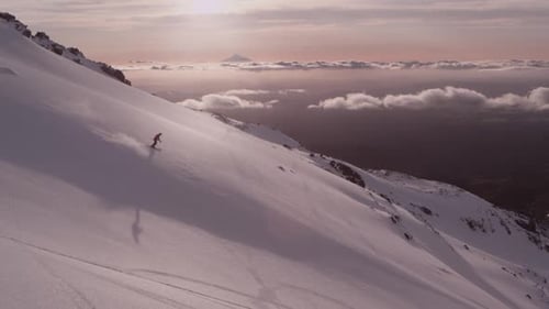Lone Skier Glides Down Snowy Mountain At Sunrise