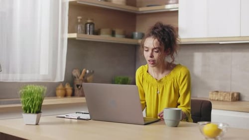 Woman Working on Laptop at Kitchen Table