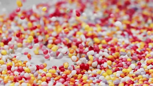 Colorful sugar pearls sprinkled in a bowl, low depth of field, slow motion, close up