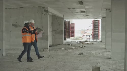 Two Construction Workers Reviewing Blueprints in Building