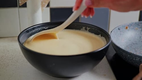 Remuez doucement la pâte à crêpes dans un bol à la main pendant le processus de cuisson au Ralenti