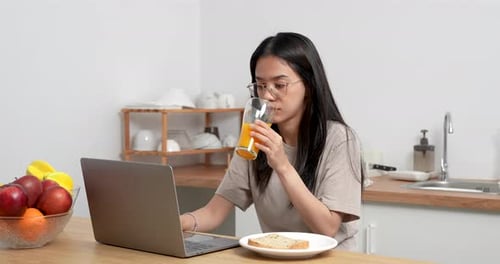 Woman Working on Laptop and Drinking Juice at Home