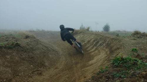 Mountain Biker Riding Dirt Bike Course on Foggy Day