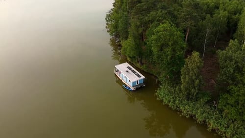 Casa flotante flotando en un lago junto a un bosque en Brandeburgo, Alemania