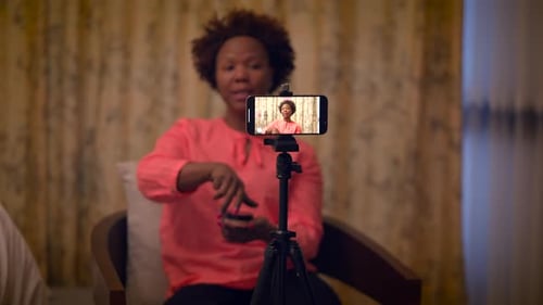 Influenciadora de maquillaje femenina graba un vídeo de un producto de belleza en un teléfono inteligente