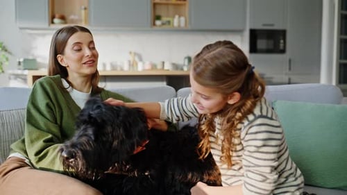 Woman and Girl Petting Dog on Sofa at Home