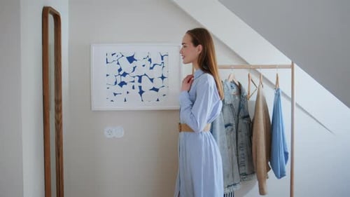 Mulher sorridente olhando o reflexo do espelho escolhendo roupa para o dia de trabalho em casa