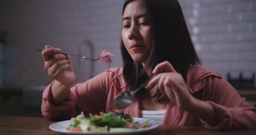 Woman Eats Healthy Salad in a Kitchen
