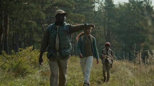 Dad Pointing at Lake when Slowly Walking down Path with Two Kids during Hike
