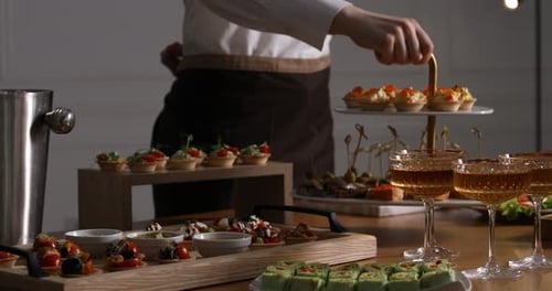 Waiter arranging appetizers for buffet at table, closeup. Camera moving right