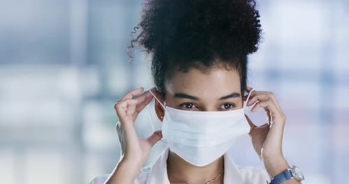 4k video footage of a young woman putting on her face mask in an office