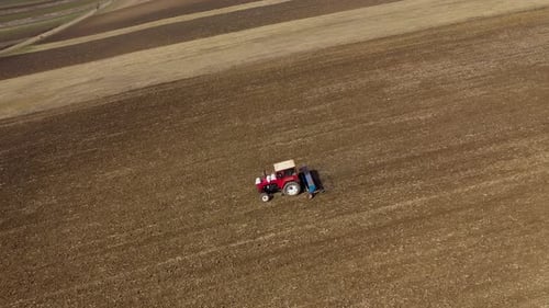 Tractor Seeding-Sowing Crops at Agricultural Field. Soil Loosening Aerial Slow Motion