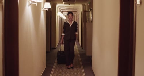 Stylish Black Woman with Suitcase Walking in Hotel Hall After Check in