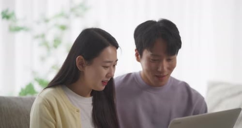 Young Adults Using Laptop Together on Sofa Indoors