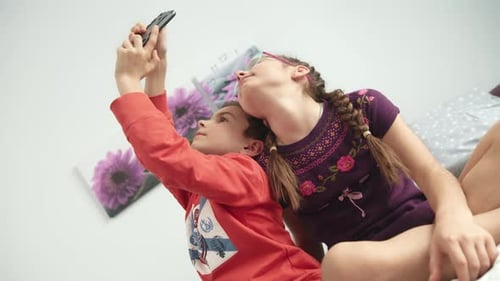 Brother and Sister Take Selfie on Bed Indoors