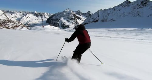 Professioneller Skifahrer, der im Winter steile verschneite Berghänge hinuntergleitet