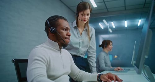 African American Technical Support Specialist Monitors Data on Computer with Colleague