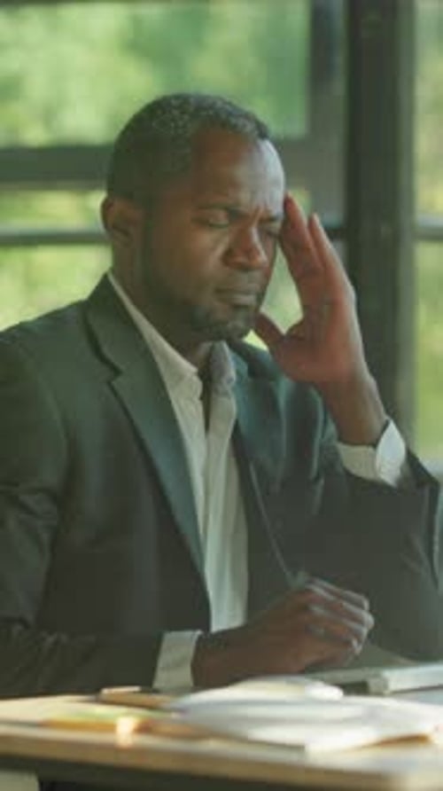 Man Struggles with Stress at Work Man in Suit Coping with Exhaustion Amidst Busy Office Environment