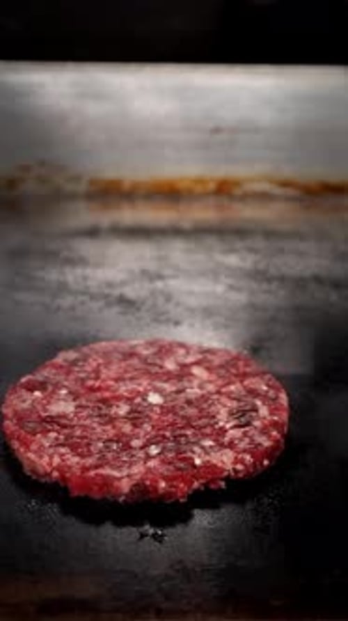Raw Beef Patty Being Placed On Grill