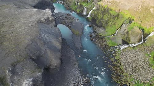 Aerial view of a river flowing through a canyon with waterfalls in Iceland.
