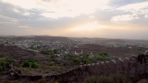 city view with dramatic sun beams orange sky and ancient fort wall at evening from mountain top vide