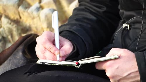 Adult Writing in a Notebook Outdoors