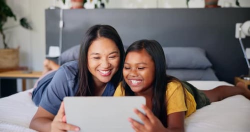 Smiling Mother and Daughter Enjoying Tablet on Bed