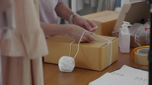 Woman Tying String Around a Shipping Box